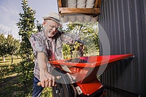 Man working with a wheel of a grape harvesting machine to squeeze many grapes