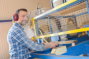 Man working with wood behind screen