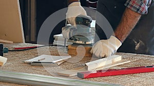 Man working with wooden planck and electric planer write in notebook.