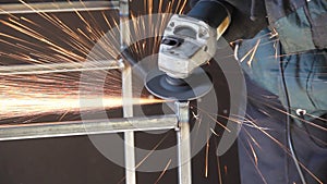 A man works with an angle grinder. Sparks from the grinder. Metal grinding process