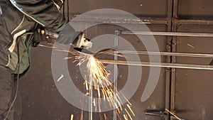 A man works with an angle grinder. Sparks from the grinder. Metal grinding process