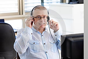 man works as a manager in an office and talks with clients on the internet through a computer with headphones with a