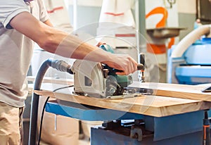 Man works with a circular saw in a carpentry workshop
