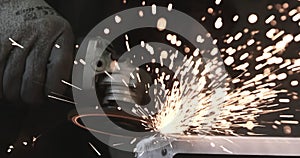 Man works circular saw. Sparks fly from hot metal. Man hard worked over the steel. Close-up slow motion shot in garage