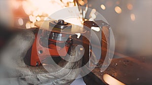 Man works circular saw. Sparks fly from hot metal. Man hard worked over the steel. Close-up slow motion shot in garage