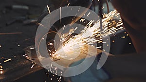 Man works circular saw. Sparks fly from hot metal. Man hard worked over the steel. Close-up slow motion shot in garage