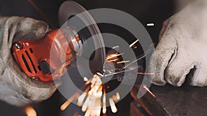 Man works circular saw. Sparks fly from hot metal. Man hard worked over the steel. Close-up slow motion shot in garage