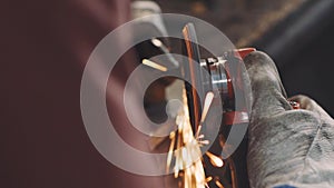 Man works circular saw. Sparks fly from hot metal. Man hard worked over the steel. Close-up slow motion shot in garage