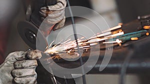 Man works circular saw. Sparks fly from hot metal. Man hard worked over the steel. Close-up slow motion shot in garage