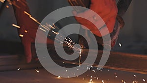 Man works circular saw. Sparks fly from hot metal. Man hard worked over the steel. Close-up slow motion shot in garage