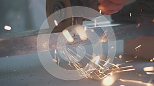 Man works circular saw. Sparks fly from hot metal. Man hard worked over the steel. Close-up slow motion shot in garage