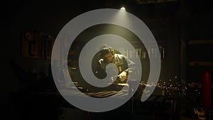 A man works with a circular saw. Worker grinder grinds metal in workshop. Sparks fly from hot metal. The man worked hard on the