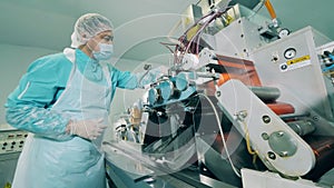 Man works with a conveying machine in laboratory. Pharmaceuticals production line at a modern facility.