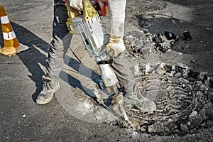 A man works with an electric jackhammer, smashes asphalt.