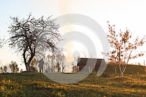 man works in the garden and picks up autumn leaves in the picturesque rural landscape