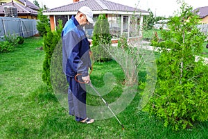 A man works in the garden, spraying weeds from a sprayer