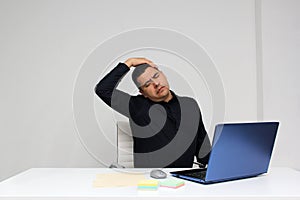 Man works in his office with his laptop, his head, neck, and back, cervical, lumbar pains due to stress, anxiety and tension
