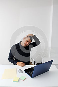 Man works in his office with his laptop, his head, neck, and back, cervical, lumbar pains due to stress, anxiety and tension