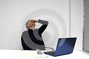 Man works in his office with his laptop, his head, neck, and back, cervical, lumbar pains due to stress, anxiety and tension