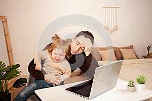 A man works at home on a laptop. The child shouts yells hysterically prevents distractions from work. The father can not