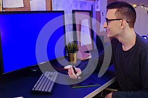 A man works at home with a tablet and pen. Griffin designer, a man looks at a green screen computer. A man works on freelance