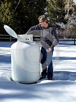 Man works on a remove large tank of Propane in winter