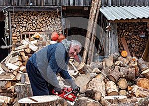 A man works with a saw, processing firewood for the winter season