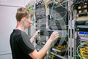 A man works in a server room. System administrator installs a new server in a modern data center.  The engineer replaces the