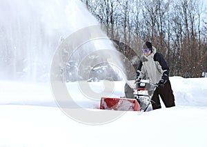 A man works snow blowing machine