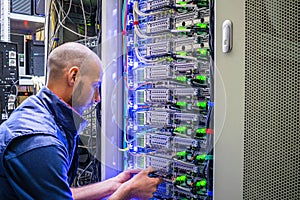 A man works with telecommunications. The technician switches the Internet cable of the powerful routers. A specialist connects