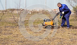 A man works in a vegetable garden in early spring. Digs the ground. Works as a cultivator, walk-behind tractor