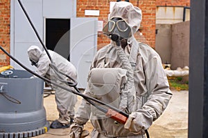 Man works in a white chemical protection suit and a gas mask.