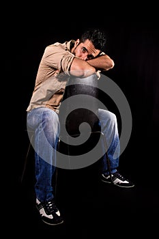 Man worried and thoughtful attitude, sitting backwards on chair with his head and arms resting on the backrest