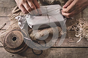 Man is wrapping a gift with natural materials and organic cotton, ecological and biodegradable