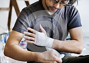 Man wrapping injured hand with bandage