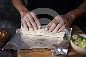 Man wraps a durum or a burrito in aluminum foil