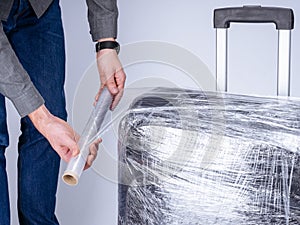 Man wraps suitcase protective film