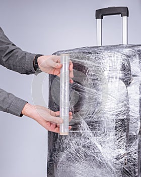 Man wraps suitcase protective film