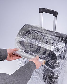 Man wraps suitcase protective film