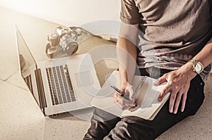 man write pen on notebook and work on laptop, a man relax working from home using notebook computer and camera, businessman plan