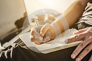 man write pen on notebook and work on laptop, a man relax working from home using notebook computer and camera, businessman plan