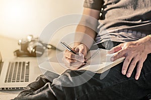 man write pen on notebook and work on laptop, a man relax working from home using notebook computer and camera, businessman plan