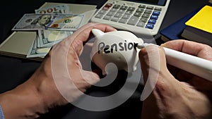 Man writes on a piggy bank pension. Savings for retirement.