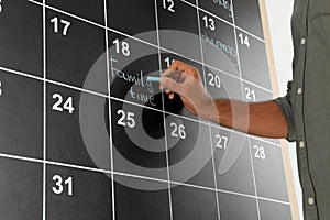 Man writing with chalk on board calendar, closeup