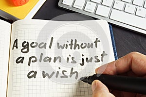 Man is writing A goal without a plan is just a wish.