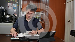 A man is writing a household ledger while organizing receipts. A close-up of hands. Tax or year-end settlement concept