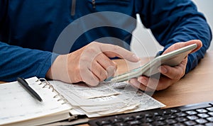 A man is writing a household ledger while organizing receipts. A close-up of hands. Tax or year-end settlement concept