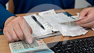 A man is writing a household ledger while organizing receipts. A close-up of hands. Tax or year-end settlement concept