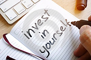 Man is writing invest in yourself. photo