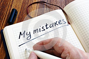 Man is writing My mistakes in a note. Inner critic.